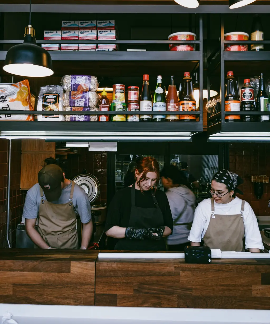 Tre i personalen arbetar bakom disken i ett café.